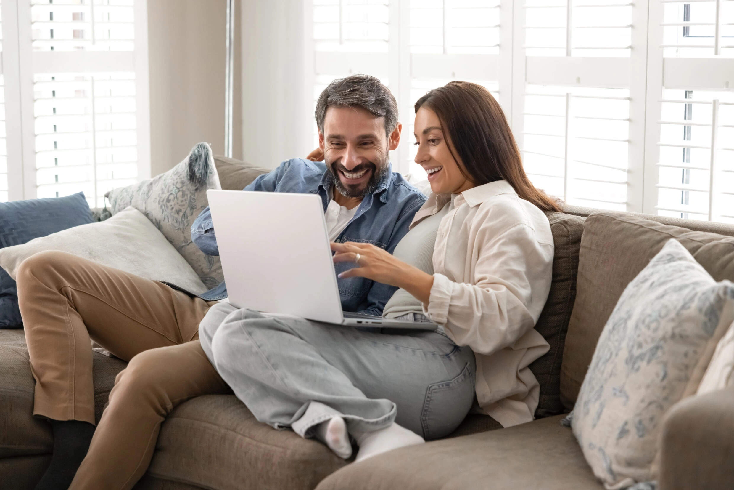 Couple in love relaxing on comfortable couch with laptop, enjoy online shopping through marketplace platform or websites