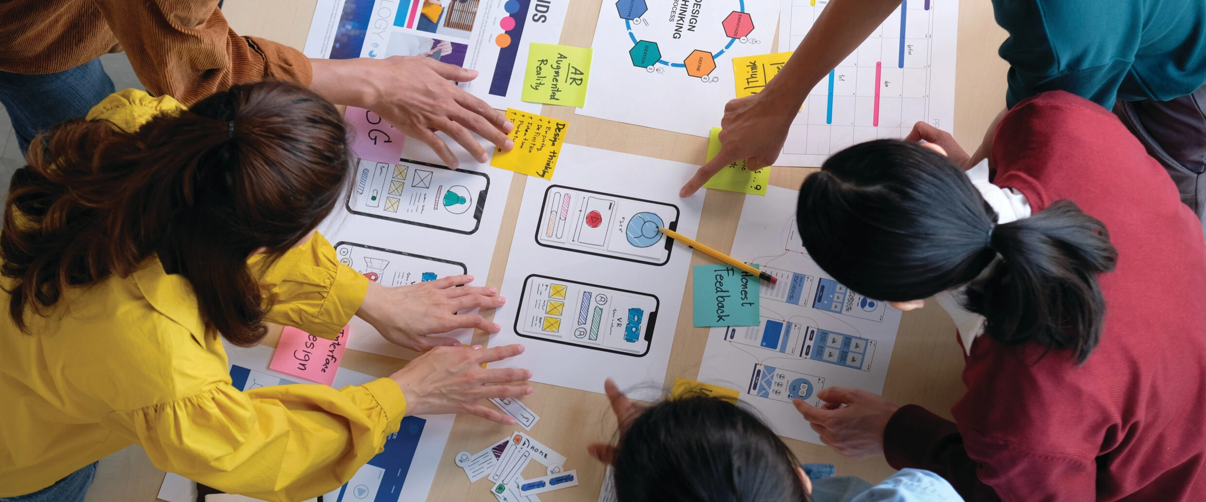 UX designers collaborating on wireframes and user flows, reviewing mobile screen layouts, interactions, and content structure during a UX design workshop.