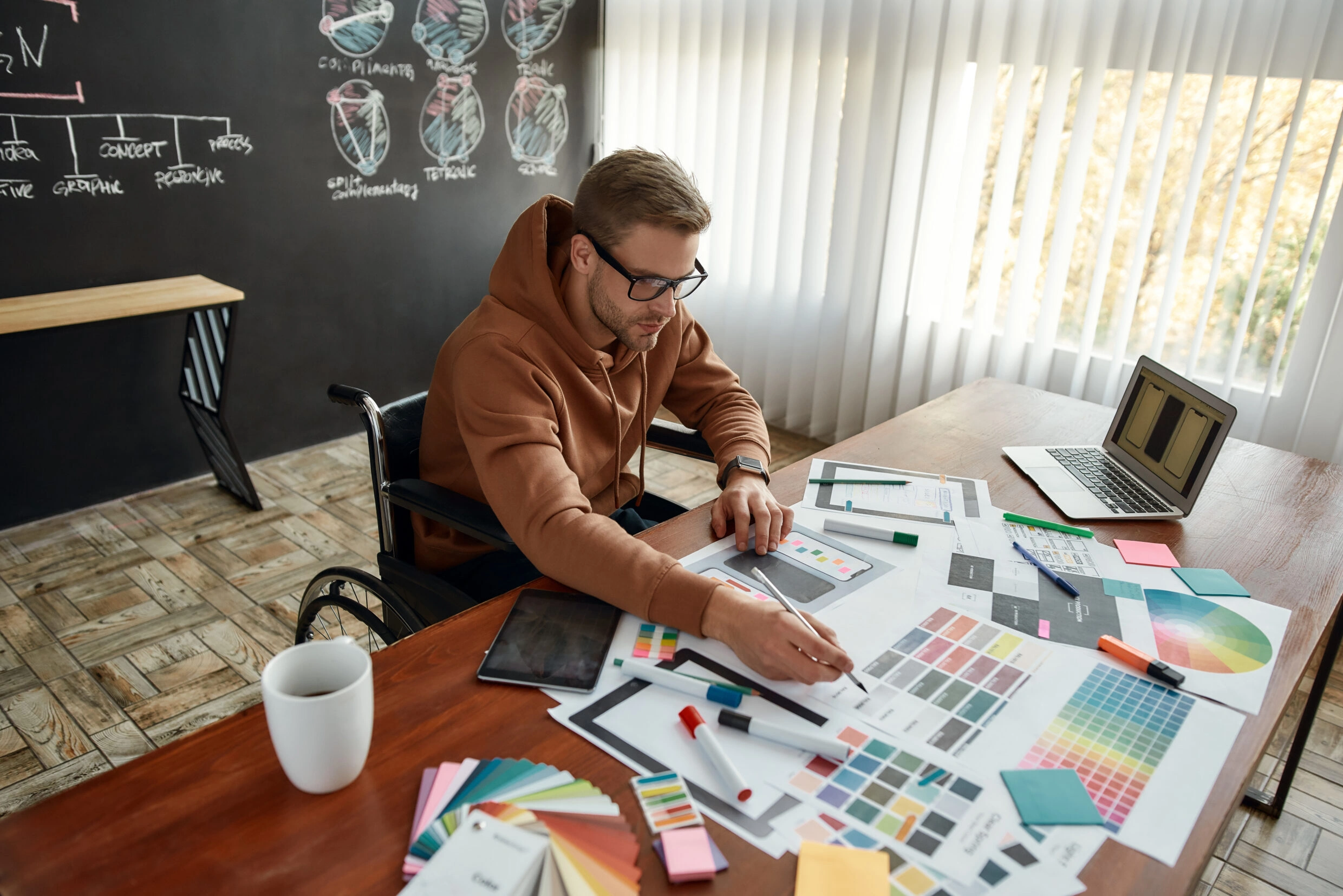 Portrait of professional male ux designer in a wheelchair picking the right colors for website