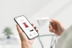 Shopper viewing a red dress on a smartphone while holding a credit card